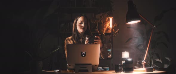 Woman examines camera while at desk