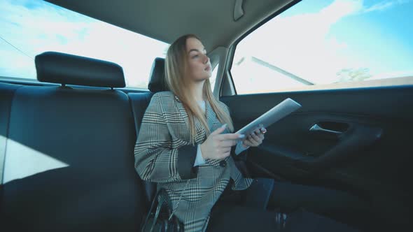 Busy Student Working with Her Tablet and Phone in Her Car