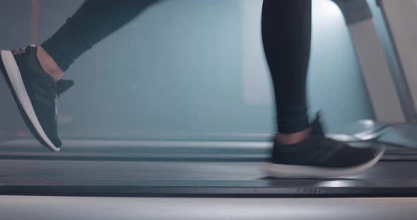 Close Up View of Female Legs in Sneakers Running on Treadmill at Gym Slow Motion