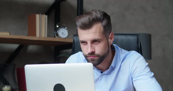 Attractive Businessman Looking Worried and Tired Infront of Laptop