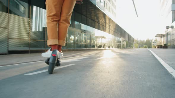 Legs of Man Riding E-Scooter in City