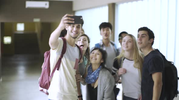 Group of students taking selfie with smartphone in corridor