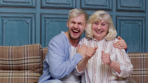 Generations Family of Senior Mother and Handsome Adult Son or Grandson Dancing Together Laughing