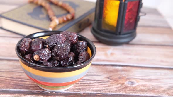 Close Up of Fresh Date Fruit in a Bowl and Holly Book of Quran on Table