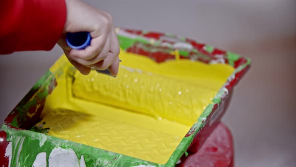 Covering a Roller in Yellow Paint in the Paint Tray