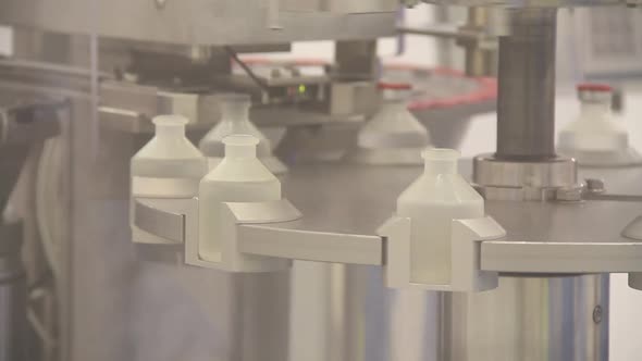 Plastic antibiotics vials being filled by machine.