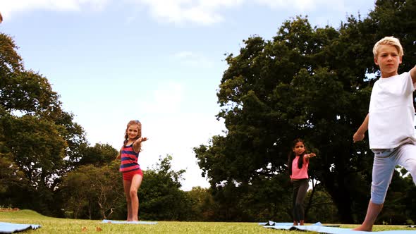 Group of kids performing stretching exercise in park