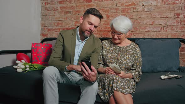 Caucasian Elderly Pensioner Mother and Her Middleaged Son Celebrating Mother's Day Sitting on a