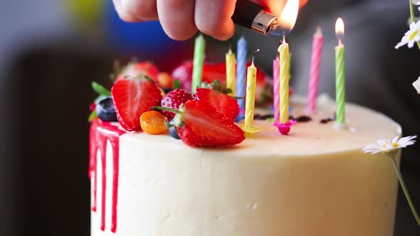 hand lighting candles in birthday cake.