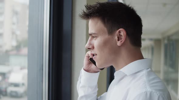 Profile of Office Manager Talks on Phone and Drinks a Cup of Coffee in Corridor