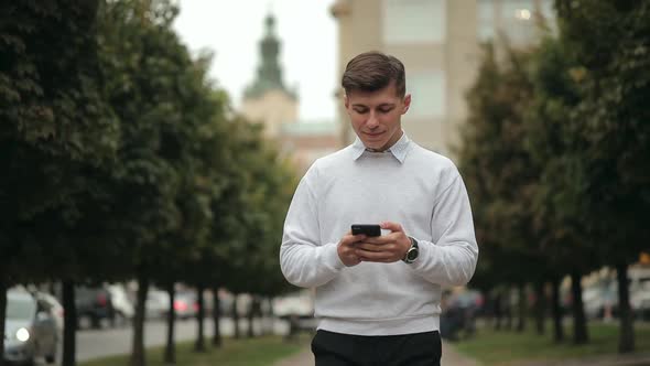 A Man is Walking and Texting on a Smartphone