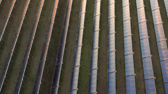 Drone Over Rows Of Sunlit Solar Panels In Countryside Field