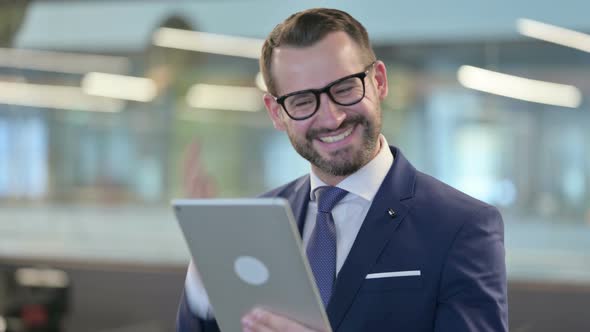 Successful Businessman Celebrating Win on Tablet