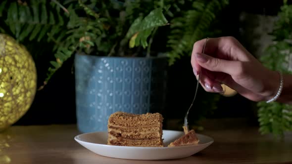 Woman holding cake dessert fork and breaks off delicious cake