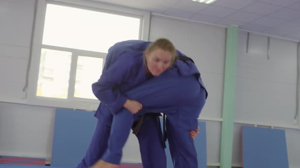 Female Jujutsu Athlete Throwing Male Partner on Mat during Sparring Fight