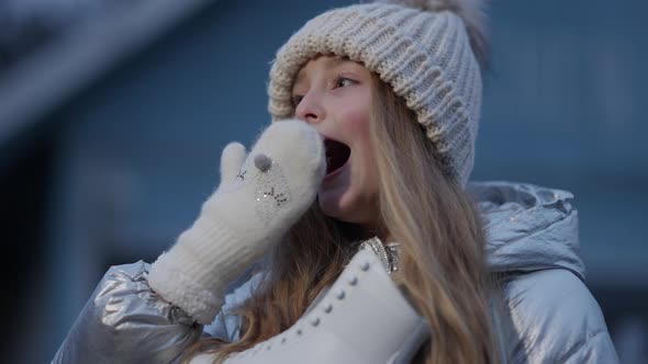 Beautiful Caucasian Little Girl Yawning and Smiling at Camera Standing on Ice Rink with Skates