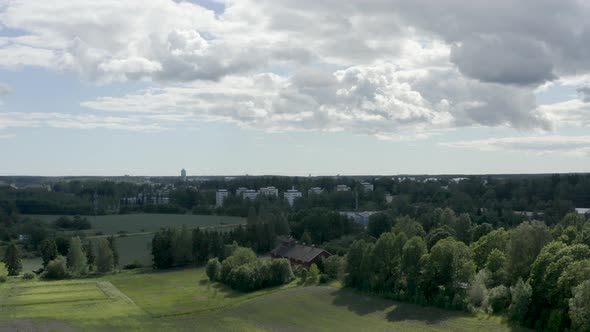 Slow aerial pan of the countryside in Kerava, Finland with a large barn and green fields.