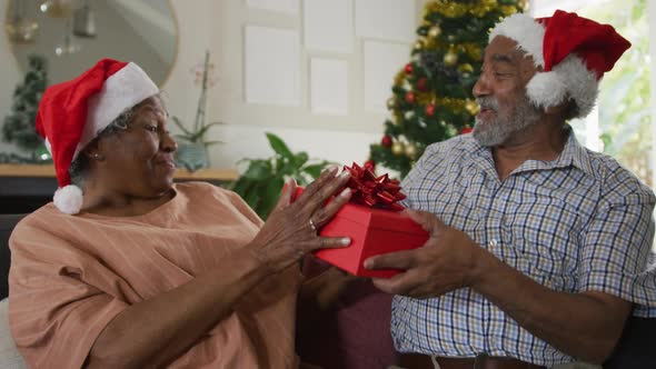 Animation of happy african american senior couple sharing with presents at christmas time