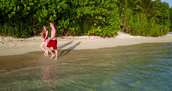 Fun boy and girl on honeymoon vacation enjoy life on beach on clean white sand background 4K