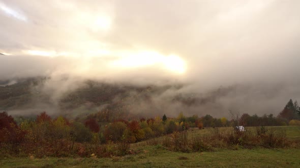 Beautiful Hills in Gloomy Gray Fog Covered with Colorful Autumn Trees in the Carpathians in