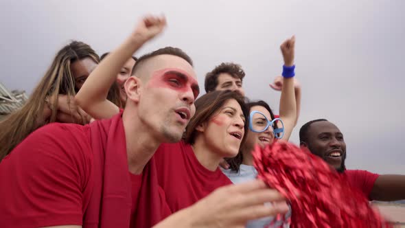 A Group of People of Different Races and Ages Follow the Soccer Game in the Stands