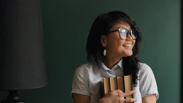 Joyful Lady in Glasses Laughs and Pulls Faces Holding Books