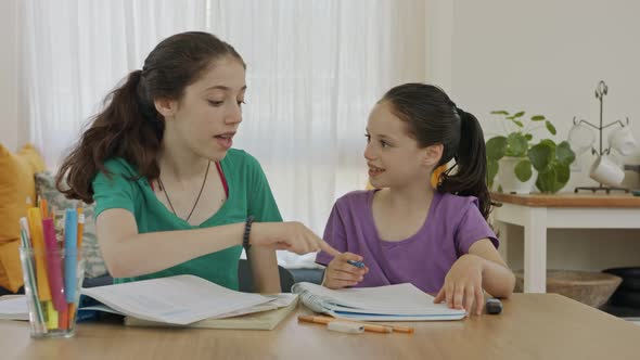 Teenage girl helping her young sister with homework during the COVID-19 pandemic