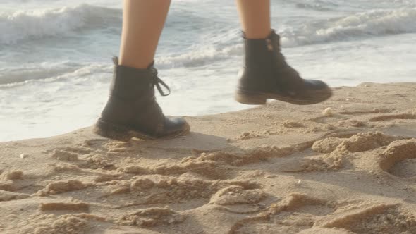 Closeup Cinematic Shot of Woman Feet in Boots Walking on the Beach at Sunset or Sunrise