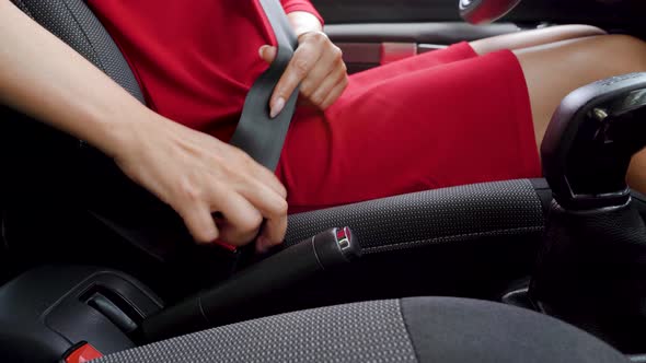 Woman in Red Dress Fastening Car Safety Seat Belt While Sitting Inside of Vehicle Before Driving