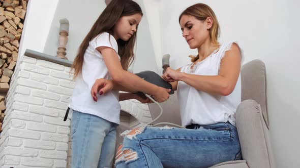 Daughter Helping Mom To Measure the Pressure with Stethoscope at Home