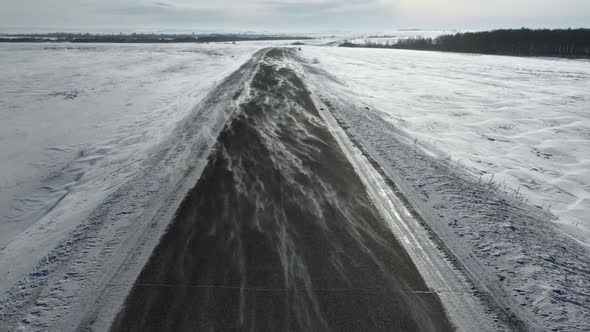 Flight at Low Altitude Over the Winter Road Wind Overtakes the Snow Across the Road