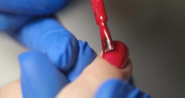 Manicurist Paints Client Nails with Bright Red Polish