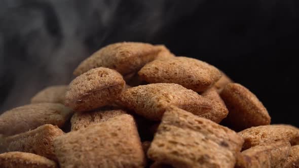 Hot crispy chocolate pads with smoke rotate on a black background. Cocoa cereal dessert