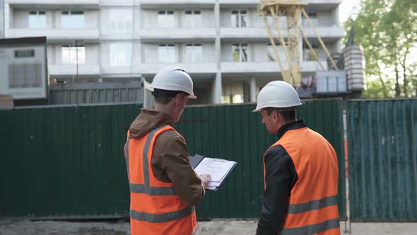 Two construction professionals discussing a construction work plan at a construction site.