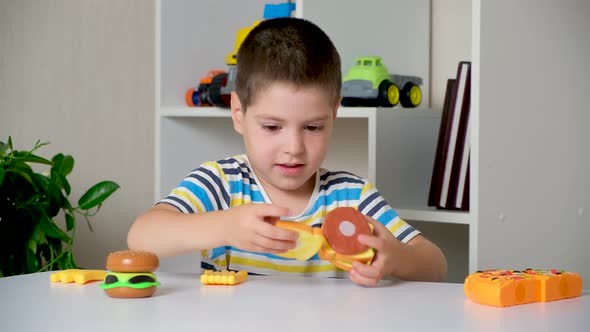 A 5Yearold Boy Plays with Plastic Food  Sandwiches and Burgers with Velcro