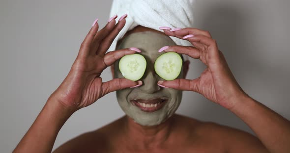 African senior woman holding cucumbers on her eyes - Beauty treatment and body care concept