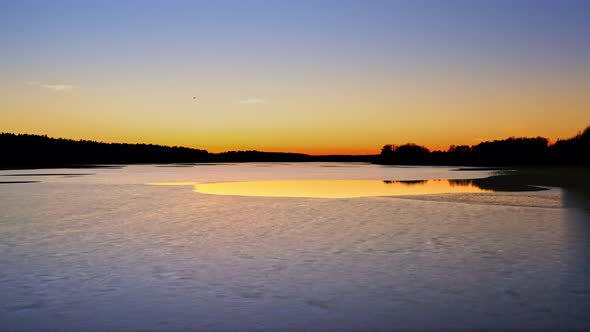 Melting ice on lake in winter at sunset, aerial view