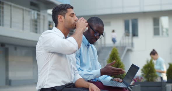 Multiethnic Office Colleagues Using Laptop Sitting on Bench Outdoor