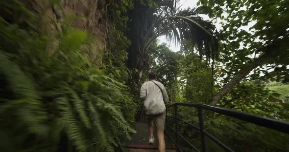 Handheld Tracking Shot of a Young Male Traveler Running on the Stairs Through the Tropical