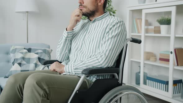 Slow Motion Portrait of Handicapped Man Sitting in Wheelchair in Apartment