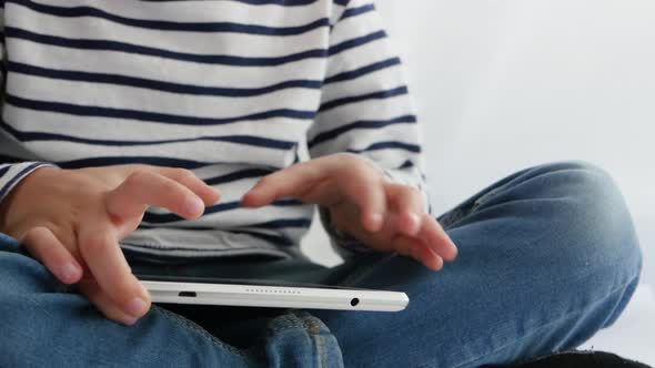 Close Up. The Child's Hands Touch the Touch Screen of the Tablet. A Little Boy Plays with a Tablet