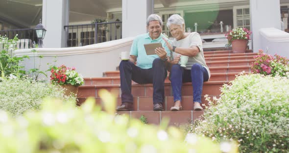 Video of happy biracial senior couple using tablet in garden