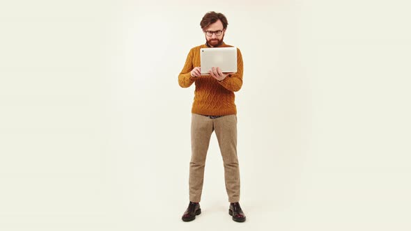 Full Shot of a Young Bearded Man Standing and Working in Laptop Studio Shot Isolated Copy Space Job