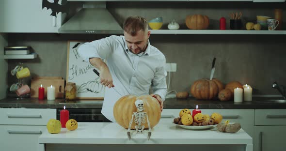 A Man Trying To Cut a Big Pumpkin at His Kitchen