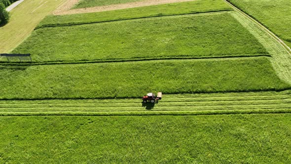 Aerial view of a tractor mowing a green fresh grass