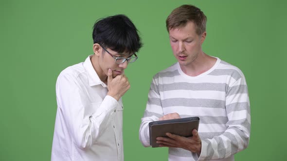 Two Young Multi-ethnic Businessmen Having Meeting with Digital Tablet Together