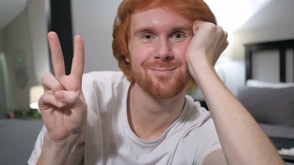 Victory Sign by Casually Sitting Redhead Man,