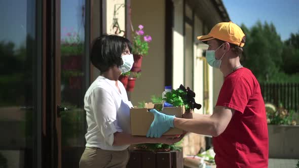 Man Courier Giving to Woman Box of Fresh Food and Farewell at Door of House Outdoors Spbd