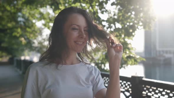 Middleaged Woman is Strolling Alone in City at Sunny Summer Day Smiling to Camera