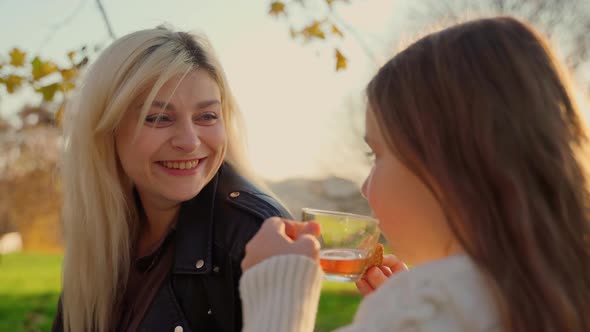 Mother and daughter on picnic at autumn park outdoors. Two females persons spending time together